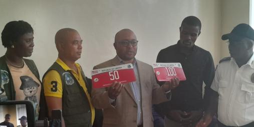 Minister Sirleaf Ralph Tyler proudly displays the newly designed Non-Revenue plates during the launch event at the Ministry of Transport.